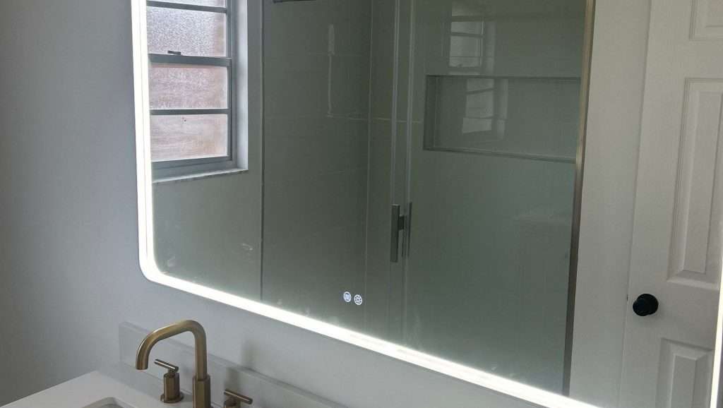 Urban Green Energy remodeling contractor installed an illuminated bathroom mirror with elegant gold fixtures in Jacksonville, Florida with a low bathroom redesign cost.