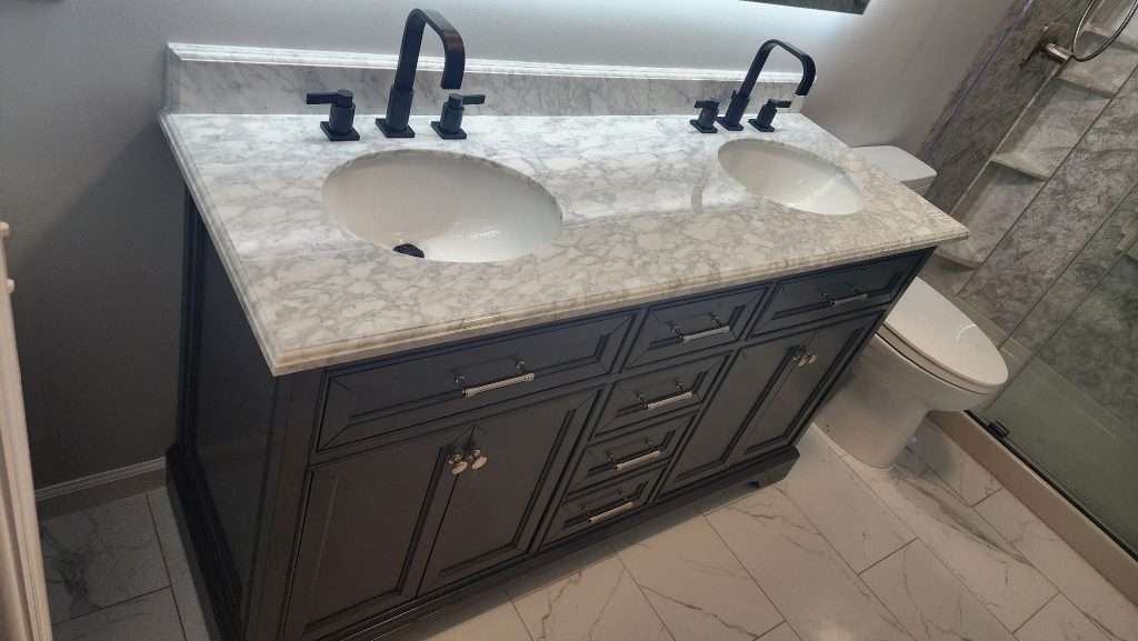 Urban Green Energy remodeling project with affordable bathroom redesign cost showcasing a luxury bathroom vanity with double sinks, marble countertop, and modern faucets in Jacksonville, Florida.